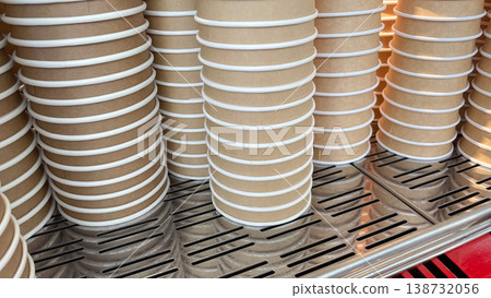 Rows of stacked brown craft paper coffee cups on a professional metal espresso machine surface Rows of stacked brown craft paper coffee cups on a professional metal espresso machine surface 138732056