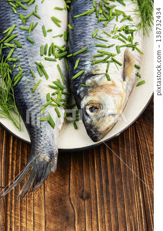 Whole salted herring fish on a wooden surface. Whole salted herring fish on a wooden surface. 138732434