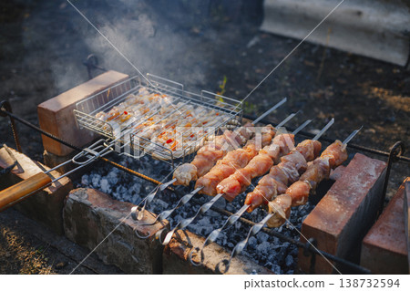 In the village, they roast shish kebab on skewers and barbecue shish kebab on the grill. Smoke is visible In the village, they roast shish kebab on skewers and barbecue shish kebab on the grill. Smoke is visible 138732594