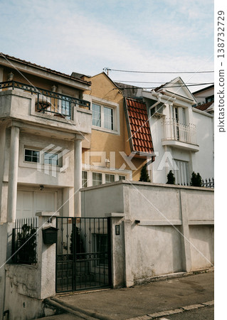 Residential houses with balconies and fence in quiet urban neighborhood under soft daylight. Ideal for real estate, architecture, suburban lifestyle and housing concepts Residential houses with balconies and fence in quiet urban neighborhood under soft daylight. Ideal for real estate, architecture, suburban lifestyle and housing concepts 138732729