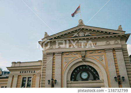 Historic Belgrade railway station facade with Serbian flag, clocks and classical details. Concept of national identity, travel and heritage architecture 138732799