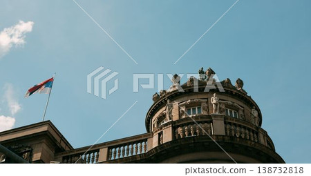 Decorative historic building dome with sculptures and Serbian flag under blue sky in Belgrade. Concept of heritage, culture and authority 138732818