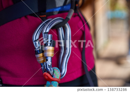Close up of metal carabiners attached to safety harness with rope Close up of metal carabiners attached to safety harness with rope 138733286