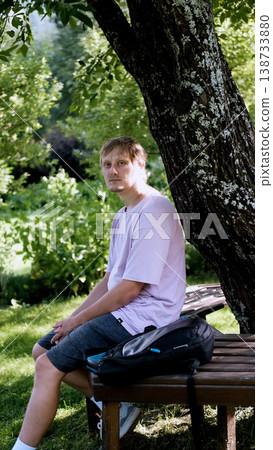 Relaxing man in a park on a bench in summer, enjoying the fresh air, vacation, or relaxing alone in the garden. A thoughtful, smiling, or calm man in nature, resting or waiting in a natural setting. Relaxing man in a park on a bench in summer, enjoying the fresh air, vacation, or relaxing alone in the garden. A thoughtful, smiling, or calm man in nature, resting or waiting in a natural setting. 138733880