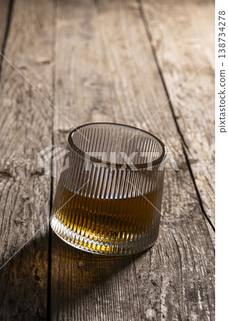 Classic whisky tumbler on aged wood background. Whiskey glass on rustic wooden surface. Classic whisky tumbler on aged wood background. Whiskey glass on rustic wooden surface. 138734278