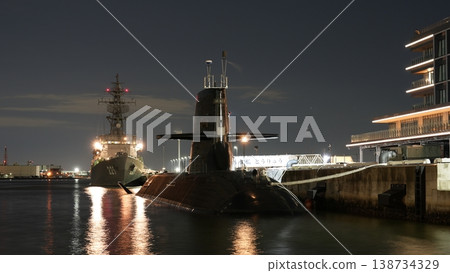 The destroyer Abukuma and the submarine Toryu are anchored in the harbor at night. 138734329