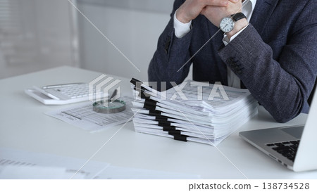Business professional at desk reviewing financial documents, calculator and laptop, focused on accounting, audit and budget planning. Audit and taxes Business professional at desk reviewing financial documents, calculator and laptop, focused on accounting, audit and budget planning. Audit and taxes 138734528