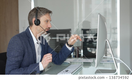 Male call center agent wearing a headset, providing online customer support and consulting clients during a video call. Business communication concept Male call center agent wearing a headset, providing online customer support and consulting clients during a video call. Business communication concept 138734592