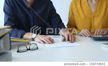 Professional accountants reviewing financial documents, using calculator and pen at modern workspace with bright lighting. Audit and taxes in business Professional accountants reviewing financial documents, using calculator and pen at modern workspace with bright lighting. Audit and taxes in business 138734641