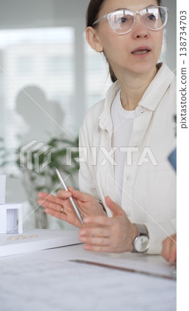 Architects discussing building plans, reviewing blueprints and architectural models, brainstorming design ideas for a new residential or commercial construction project 138734703