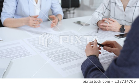 Business partners discussing legal contracts and partnership agreements, reviewing terms, collaborating on documents during an important professional meeting in an office setting Business partners discussing legal contracts and partnership agreements, reviewing terms, collaborating on documents during an important professional meeting in an office setting 138734709