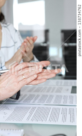 Business people applauding a successful deal with hands clapping over legal contracts, celebrating agreement and teamwork during a corporate meeting or negotiation 138734762