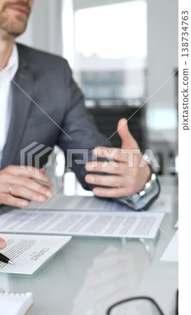 Business people engaging in a meeting, discussing important contract terms and financial agreements, clarifying legal details, signing documentation, and collaborating on corporate projects 138734763