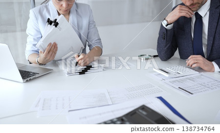 Professional auditors reviewing financial paperwork, using magnifying glass and calculator while analyzing business documents for detailed inspection and accounting compliance. Audit and taxes Professional auditors reviewing financial paperwork, using magnifying glass and calculator while analyzing business documents for detailed inspection and accounting compliance. Audit and taxes 138734764