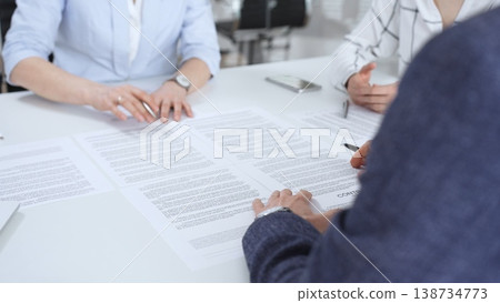 Business partners discussing legal contracts and partnership agreements, reviewing terms, collaborating on documents during an important professional meeting in an office setting 138734773