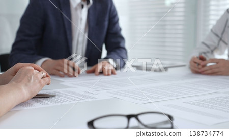 Corporate professionals reviewing important legal papers and financial statements during a structured business meeting, signifying strategy, negotiation, and successful deal closures 138734774