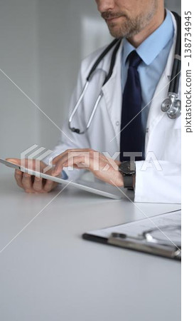 Doctor man interacting with patient during consultation, using digital tablet for modern medical healthcare technology. Medicine, healthcare and science concept Doctor man interacting with patient during consultation, using digital tablet for modern medical healthcare technology. Medicine, healthcare and science concept 138734945