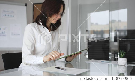 Professional businesswoman in white blouse and glasses attending corporate meeting. Deeply reflecting on business strategy. Making informed decisions. Concentrating on data analysis Professional businesswoman in white blouse and glasses attending corporate meeting. Deeply reflecting on business strategy. Making informed decisions. Concentrating on data analysis 138734966