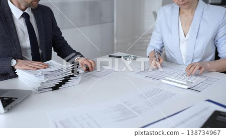 Professional accountant team analyzing corporate financial data, managing paperwork, and preparing tax reports, collaborating on bookkeeping and auditing tasks at a desk. Audit and taxes Professional accountant team analyzing corporate financial data, managing paperwork, and preparing tax reports, collaborating on bookkeeping and auditing tasks at a desk. Audit and taxes 138734967