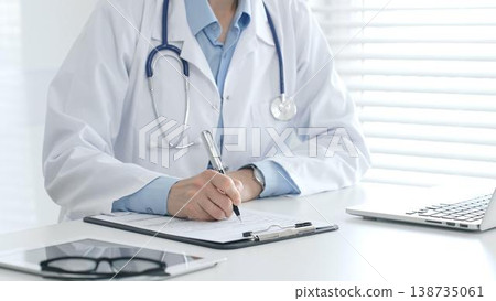 Female doctor documenting patient information while working with digital devices in a minimalist white workspace. Medicine and health care concept Female doctor documenting patient information while working with digital devices in a minimalist white workspace. Medicine and health care concept 138735061