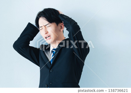 一個身穿西裝的年輕男子雙手抱頭。 138736621