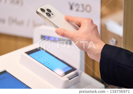 A software engineer at a foreign company uses his smartphone to pay at the self-checkout counter in the company cafe. A software engineer at a foreign company uses his smartphone to pay at the self-checkout counter in the company cafe. 138736971
