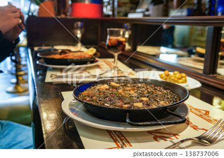 A scene of enjoying squid ink paella and red wine at a counter seat in Madrid. 138737006
