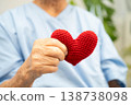 Asian elder senior woman patient holding red heart in hospital. 138738098