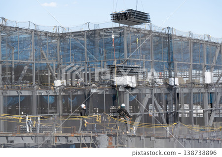 兩名工人引導起重機吊起的地板材料，並在施工現場進行卸貨作業。 138738896