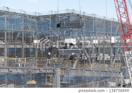 五名工人引導起重機吊起的地板材料，然後將其放到建築工地的地面上。 138738899