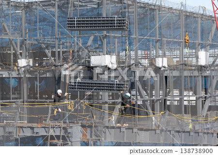 在建築工地上，六名工人引導起重機吊起的地板材料，然後將其放到地面上。 138738900