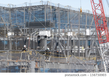 在建築工地上，九名工人引導起重機吊起的地板材料，然後將其放到地面上。 138738903