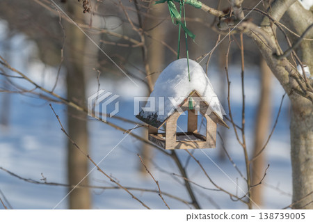 Handcrafted wooden bird feeder with frosty accents and warm lighting. Decorative garden piece featuring snowdusted wood and soft background lighting for seasonal charm 138739005