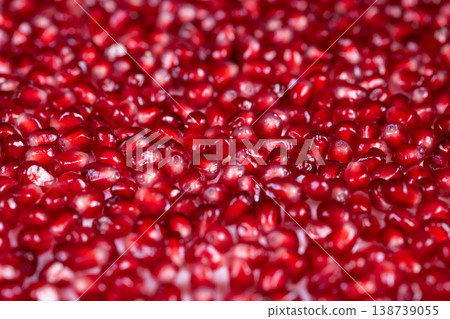 Bright pomegranate seeds jewel like surface shimmering arils scattered like gems, glamorous still life, soft bokeh, rich crimson tones, premium cosmetic inspiration 138739055