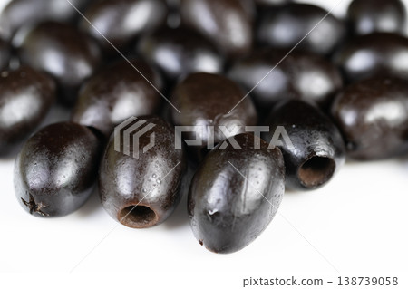 Black olives with shine and texture. Closeup of glossy black olives on bright white background. Detailed view of pitted black olives featuring shining surface and crisp lighting 138739058