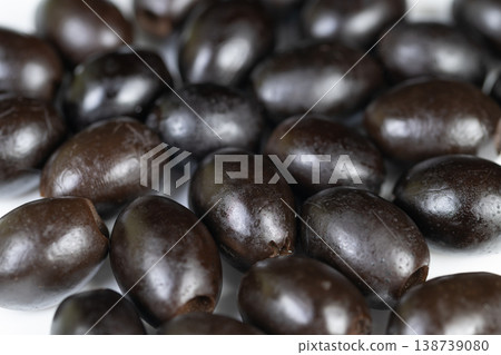 Olive texture closeup. Black olives surface detailed view. Macro photography capturing olive skin and oil. High detail shot emphasizing olive surface and sheen features Olive texture closeup. Black olives surface detailed view. Macro photography capturing olive skin and oil. High detail shot emphasizing olive surface and sheen features 138739080