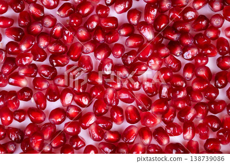 Bright pomegranate seeds arranged in festive pattern, seasonal decoration concept for holiday recipes, rich crimson tiles create eyecatching background and bold color contrast 138739086