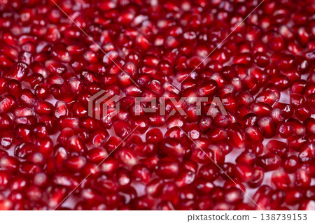 Bright pomegranate seeds arranged in repeating mosaic, smooth surface reflections create jewellike backdrop, saturated red tones suit packaging and branding use 138739153