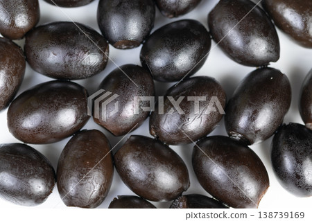 Shiny black olives on white background. Closeup of glossy black olives arranged tightly. Studio shot showing textured olives with oil sheen against white backdrop 138739169