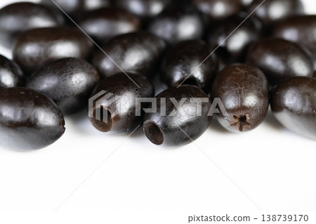 Closeup of pitted black olives with characteristic marks. Highresolution image capturing black olives with distinctive hollow centers and preservation texture details Closeup of pitted black olives with characteristic marks. Highresolution image capturing black olives with distinctive hollow centers and preservation texture details 138739170