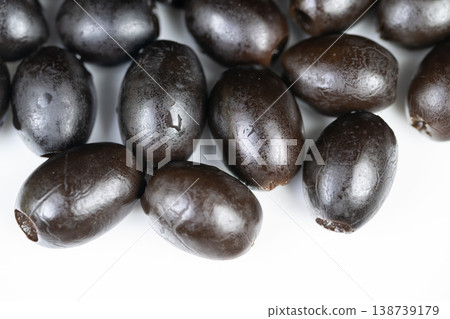 Black olives closeup. Visual focus on fresh black olives with water droplets. Detailed image of moist black olives highlighting surface texture and gloss for marketing purposes 138739179