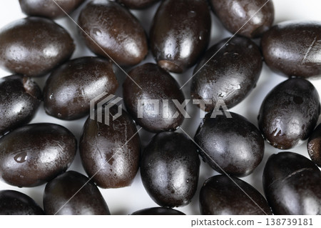 Olives shine brightly. Shiny black olives closeup shot. Glossy black olives highlighted against clean background. Detailed closeup of luminous black olives on white surface Olives shine brightly. Shiny black olives closeup shot. Glossy black olives highlighted against clean background. Detailed closeup of luminous black olives on white surface 138739181