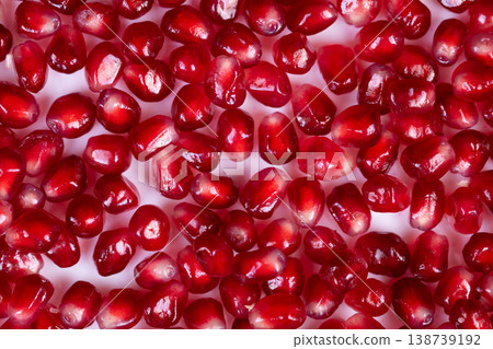 Bright pomegranate seeds macro closeup revealing translucent arils, food stylist study of shine and surface detail, studio lighting highlights glossy facets and tiny juice droplets 138739192
