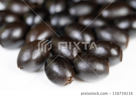 Closeup of smooth black olives with sheen. Highcontrast studio shot of shiny Mediterranean olives. Detailed image highlighting glossy surface and oil sheen of black olives 138739216