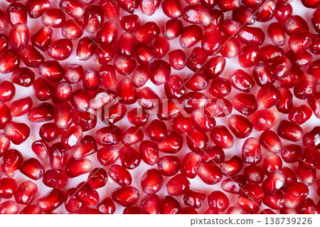 Chef sprinkles bright pomegranate seeds. Juicy arils adorn creamy dessert surface beautifully. Culinary presentation features vibrant arils enhancing elegance of sweet course 138739226