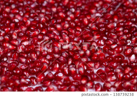 Bright pomegranate seeds romantic dessert garnish mood scattered arils on white surface with sensual highlights, evokes celebration and indulgence, perfect for holiday food styling 138739238