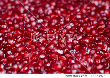 Luminous crimson seeds under moody atmospheric lighting and textured surface. Radiant pomegranate pieces highlighted by intense shadows creating upscale gourmet ambiance 138739259