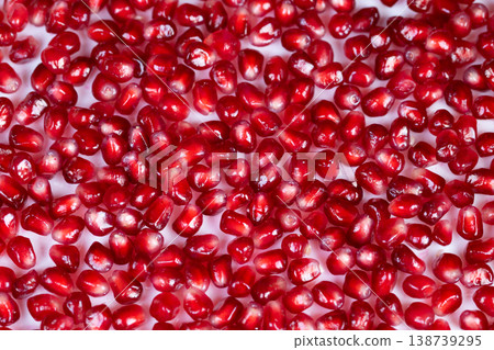 Closeup bright pomegranate seeds glistening on white surface, tight texture of glossy arils, highcontrast studio light, food styling for chef ingredient, superfood appeal 138739295
