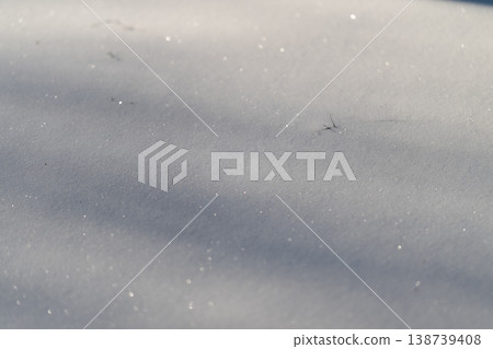 Snow glistens brightly. Frozen surface shines with tiny crystal reflections. Icy ground sparkles gently with microcrystals and subtle shadows in bright winter light 138739408