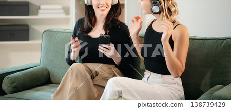 Two women collaborating on a project at home, brainstorming with a laptop and notebook in a cozy setting. 138739429